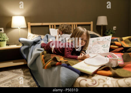 Smiling little girl lying on drawing something Stock Photo