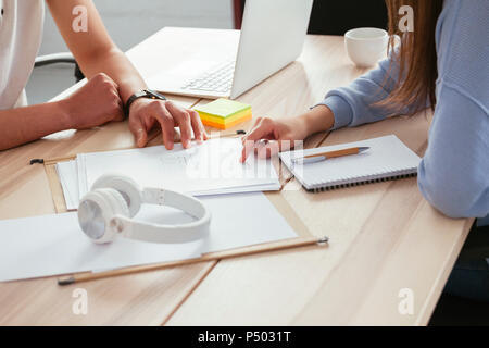 Close-up of colleagues working together at desk in office discussing papers Stock Photo