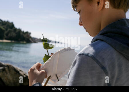 Boy with self-made toy boat in front of the sea Stock Photo