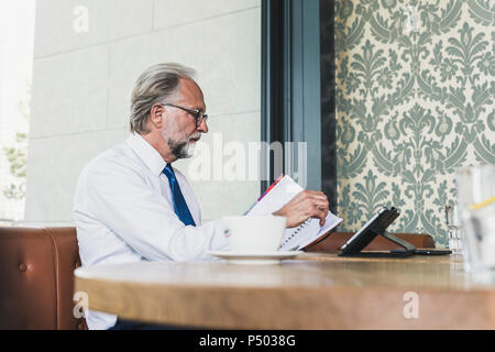 Mature businessman working at table in a cafe Stock Photo