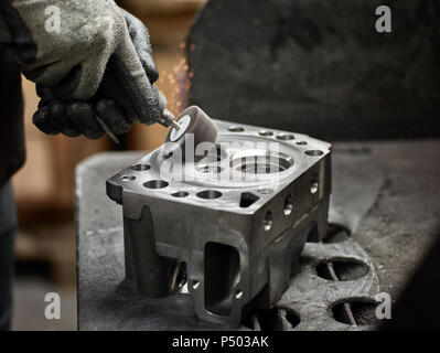 Worker in metalworking factory grinding cylinder head Stock Photo