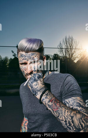 Portrait of tattooed young man smoking a cigarette Stock Photo