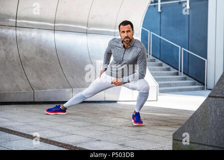 Man doing stretching exercise in the city Stock Photo