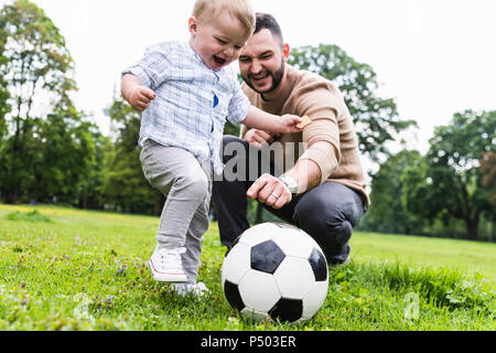 Happy father playing football with son in a park Stock Photo