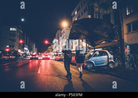 Back view of young couple with black flag walking on the street by night Stock Photo