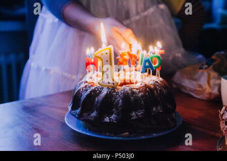 Woman lightning birthday cake candles, partial view Stock Photo