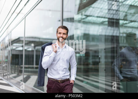Portrait of smiling young businessman at glass facade Stock Photo