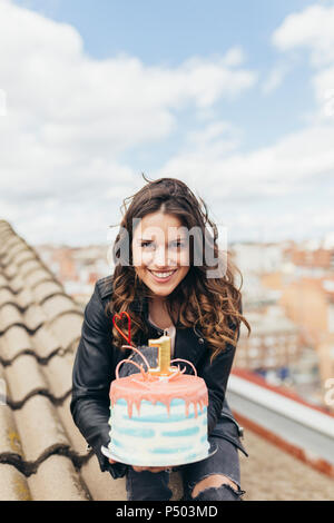 Portrait of woman presenting Birthday cake on roof