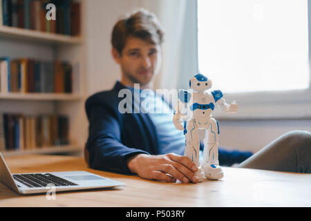 Man sitting at table with robot Stock Photo
