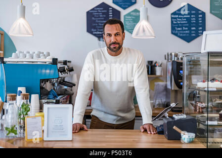 Portrait of confident owner behind the counter of a cafe Stock Photo