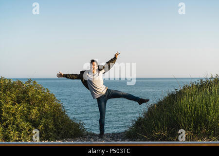 Spain, young man jumping in the air at the beach Stock Photo