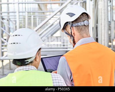 Architect and foreman with tablet wearing hards hat on construction site Stock Photo