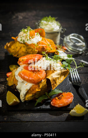 Baked Potato, sweet potato, Argentine red shrimp, sour cream on slate Stock Photo