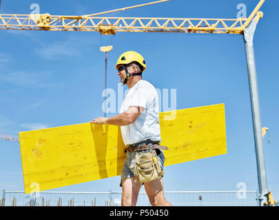 Construction worker carrying plywood construction site Stock Photo