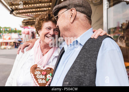 Happy senior couple with gingerbread heart on fair Stock Photo