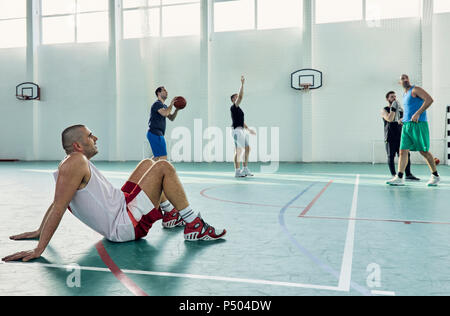 Basketball player sitting on court Stock Photo