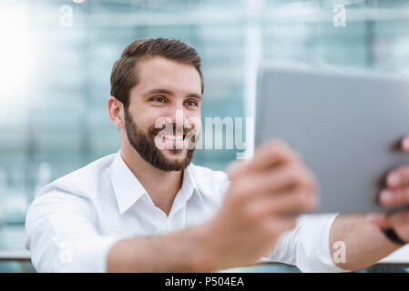 Smiling young man taking a selfie with tablet Stock Photo
