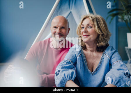 Portrait of smiling couple at teepee indoors Stock Photo