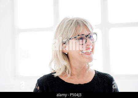 Laughing mature woman wearing glasses looking sideways Stock Photo