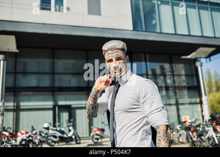 Young businessman with tattooed face walking in the city, portrait Stock Photo