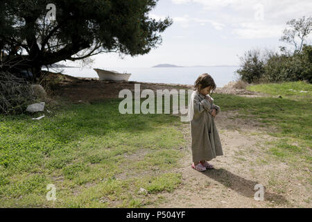 Little girl wrapped in oversized cardigan standing on a meadow Stock Photo