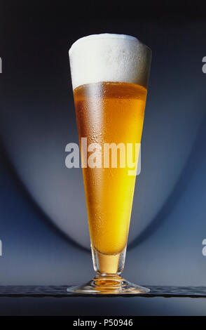 Tall glass of beer on blue background. Stock Photo