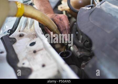 Car mechanic changing engine oil in a dirty engine Stock Photo
