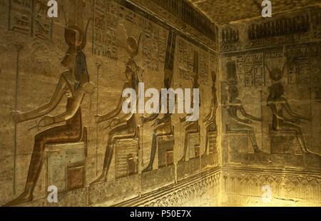 Ptolemaic temple of Hathor and Maat. Polychrome reliefs that decorate the interior. Seated gods. Deir el-Medina. Egypt. Stock Photo