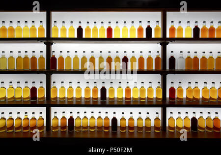 Colorful whiskey bottles on shelf against bright white light Stock Photo
