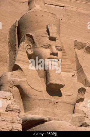 ARTE EGIPCIO. EGIPTO. COLOSO de la fachada del Templo de Ramsés II (templo mayor). Representa al faraón sentado, con el nemes en la cabeza, doble corona, las manos apoyadas en las caderas y rostro sonriente. Abu Simbel. Stock Photo