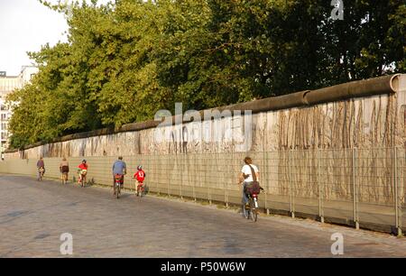 People cycling along the Berlin Wall in Niederkirchner Street. Berlin. Germany. Stock Photo