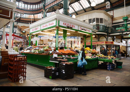 A shopper makes a purchase from a fruit and vegetable vendor at the indoor Kirkgate Market in the English city of Leeds, Yorkshire, United Kingdom. Stock Photo