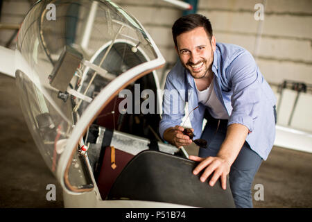 Handsome young pilot checking airplane  in the hangar Stock Photo