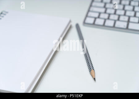 the keyboard, a clipboard and a pencil  on a white surface