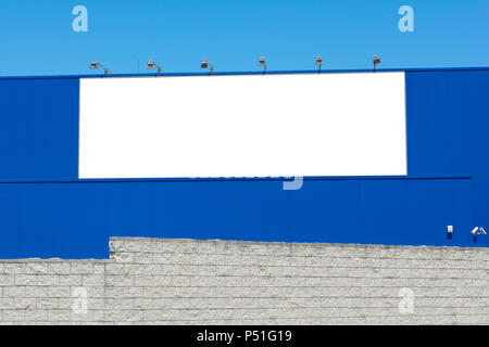 Blank billboard on brick and blue wall, banner edge and grommets preserved for a more realistic look Stock Photo