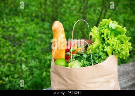 Full paper bag of healthy products stands on the wooden table. Side view. Stock Photo