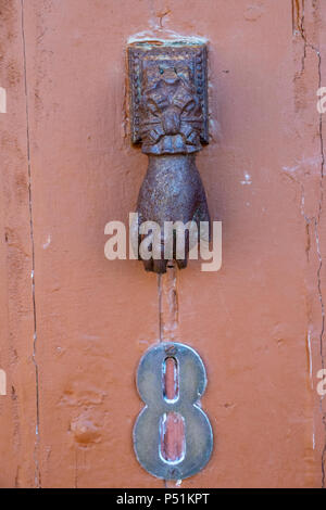 Rusty hand shaped iron door knocker on a house door in Le Faou, Brittany, France Stock Photo