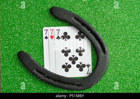 A horseshoe and three number seven cards on a green background