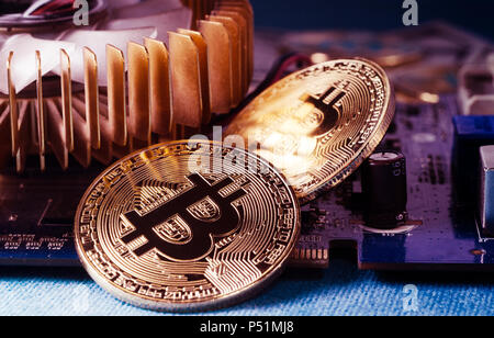 Physical Gold Bitcoin Coin on a computer video card. New independent worldwide cryptocurrency. Stock Photo