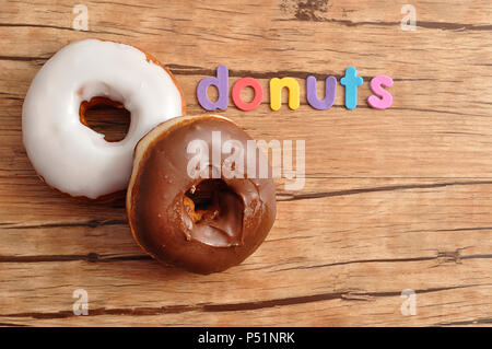 Two donuts with the word donuts on a wooden background Stock Photo