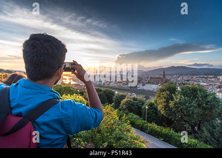 Florence, Tuscany, Italy: Tourist takes a picture with smartphone of amazing Florence cityscape from Piazzale Michelangelo at sunset Stock Photo