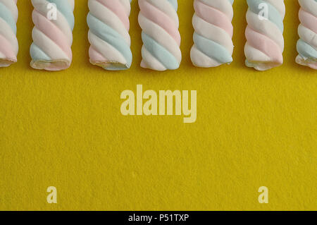 A row of pastel colored marshmallows on a yellow background Stock Photo