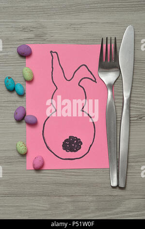 An Easter place setting with a knife and fork displayed on a table with an easter bunny card and specked easter eggs Stock Photo