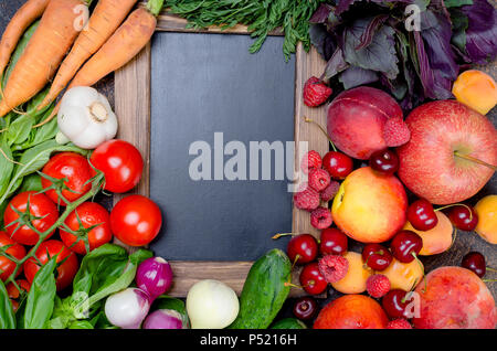 many mixed different seasonal vegetables, fruits and berries around an empty black frame, top view, copy space Stock Photo
