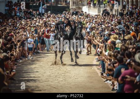 Ciutadella, Spain. 24 June, 2018:  Two 'caixers' (horse riders) gallop together with their arms entwined during the training session for the 'Jocs des Pla' (medieval tournament) during the traditional 'Sant Joan' (Saint John) festival in Ciutadella de Menorca Credit: Matthias Oesterle/Alamy Live News Stock Photo