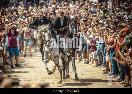 Ciutadella, Spain. 24 June, 2018:  Two 'caixers' (horse riders) gallop together with their arms entwined during the training session for the 'Jocs des Pla' (medieval tournament) during the traditional 'Sant Joan' (Saint John) festival in Ciutadella de Menorca Credit: Matthias Oesterle/Alamy Live News Stock Photo