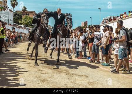 Ciutadella, Spain. 24 June, 2018:  Two 'caixers' (horse riders) gallop together with their arms entwined during the training session for the 'Jocs des Pla' (medieval tournament) during the traditional 'Sant Joan' (Saint John) festival in Ciutadella de Menorca Credit: Matthias Oesterle/Alamy Live News Stock Photo