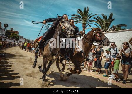 Ciutadella, Spain. 24 June, 2018:  Two 'caixers' (horse riders) gallop together with their arms entwined during the training session for the 'Jocs des Pla' (medieval tournament) during the traditional 'Sant Joan' (Saint John) festival in Ciutadella de Menorca Credit: Matthias Oesterle/Alamy Live News Stock Photo