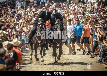 Ciutadella, Spain. 24 June, 2018:  Two 'caixers' (horse riders) gallop together with their arms entwined during the training session for the 'Jocs des Pla' (medieval tournament) during the traditional 'Sant Joan' (Saint John) festival in Ciutadella de Menorca Credit: Matthias Oesterle/Alamy Live News Stock Photo