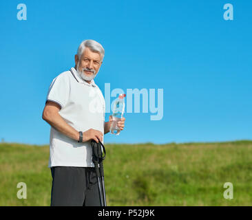 Walking with tracking sticks on fresh air between grassy hills. Wearing ...